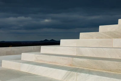 White architectural steps beneath dark storm clouds by the sea