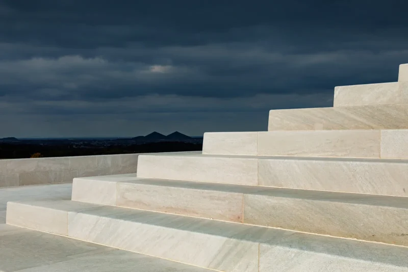 White architectural steps beneath dark storm clouds by the sea