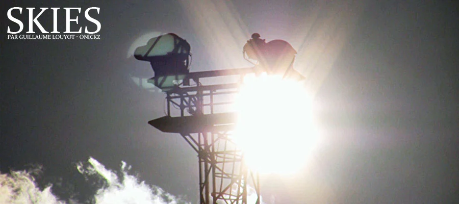 Projecteur sur un toit en silhouette devant le soleil et les nuages.